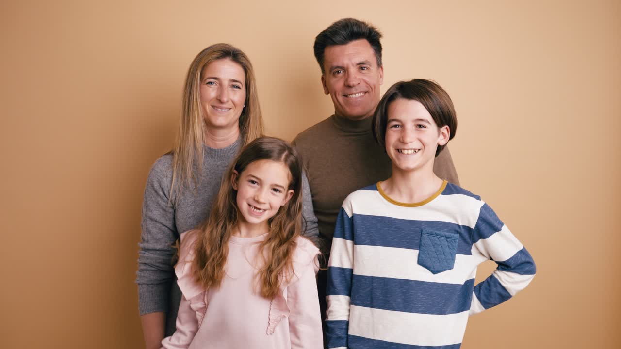 Glad familie på fire smiler og poserer i studie