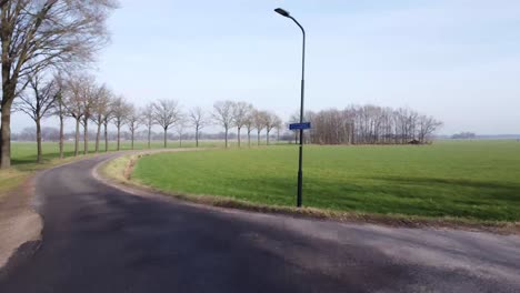 backwards drone shot of farm land with road