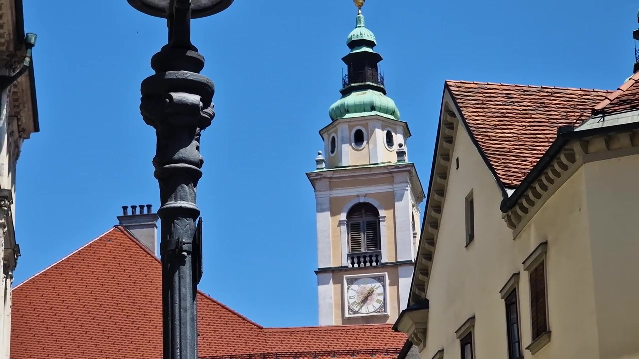 Lublana, Słowenia. Dzwonnica i wieża zegarowa rzymskokatolickiej Katedry św. Mikołaja na Starym Mieście w słoneczny dzień.