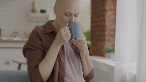 pregnant woman with bald head drinking coffee/tea