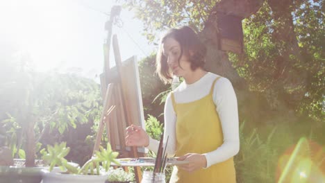 Caucasian-woman-with-brown-hair-painting-in-sunny-garden