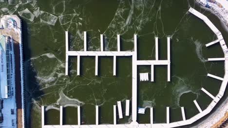 Top-down-aerial-shot-of-frozen-docks-in-a-harbor-on-Lake-Ontario-in-Mississauga