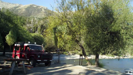 jeep driving backwards from mountainous campsite by the lake, static