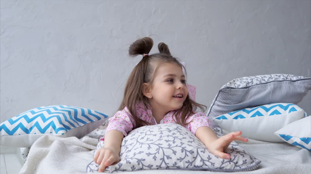 Bambina che si rilassa su un letto con cuscini