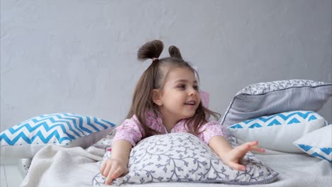 little girl relaxing on a bed with pillows