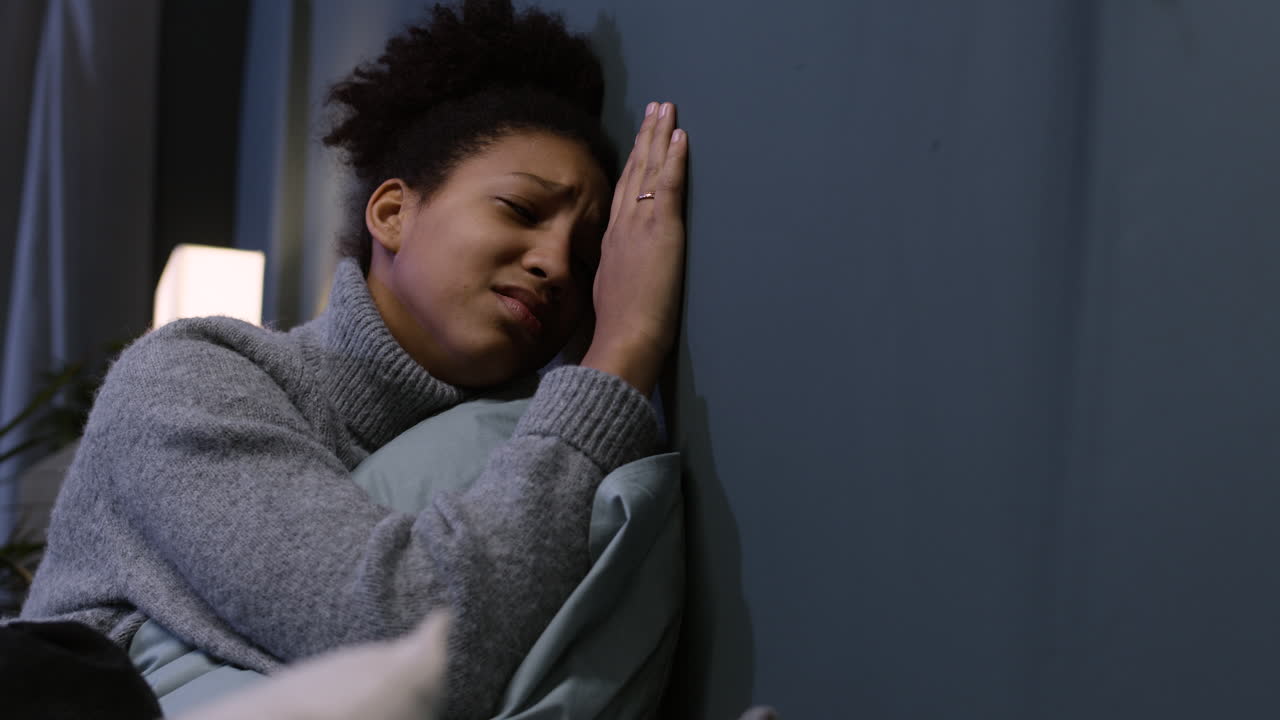 Unhappy woman hugging a pillow on her bed