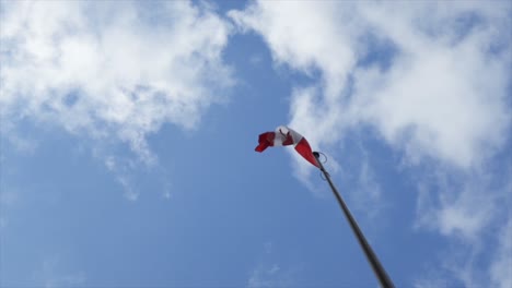 Canadian-flag-flying---waving-in-a-cloudy-blue-sky,-in-slow-motion