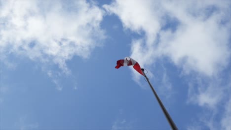 canadian flag flying - waving in a cloudy blue sky, in slow motion