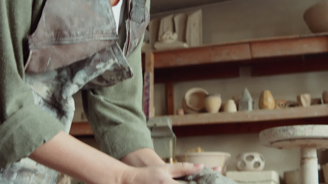 女性の陶芸家がワイヤで粘土を切る