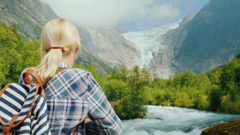 a female traveler looks at the beautiful mountains and glacier on top briksdal glacier in norway the