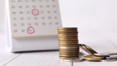 stack of coins and calendar on white background