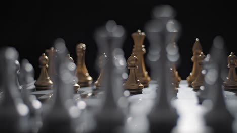 shallow depth shot from behind silver chess pieces of gold pawn moved forward