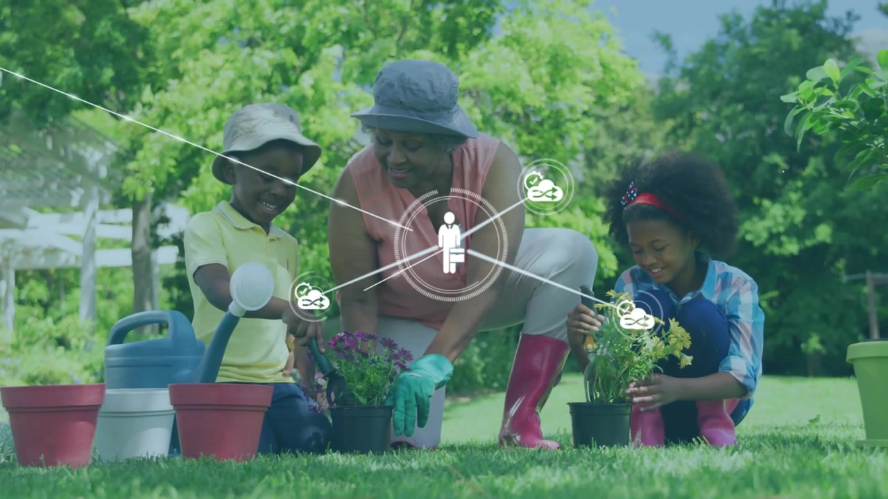 African American Grandmother and Grandchildren Planting Flowers in Garden
