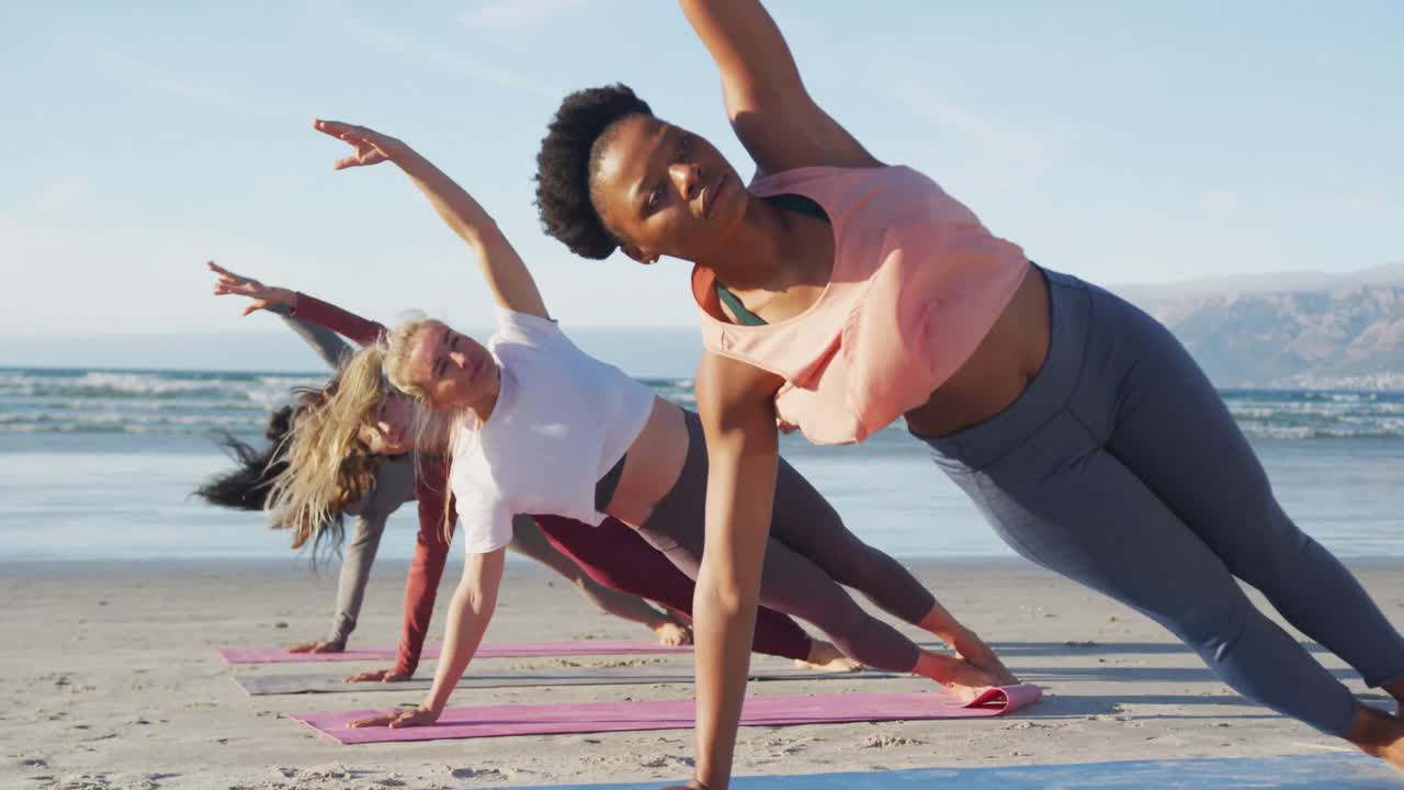 Group of diverse female friends practicing yoga at the beach