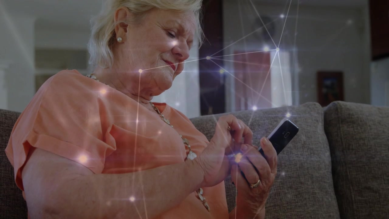 Donna anziana che tocca il telefono, attivando nodi e linee tecnologiche, la telecamera si allontana mentre legge i messaggi.
