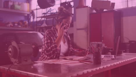 video of biracial woman using smartphone and laptop in workshop