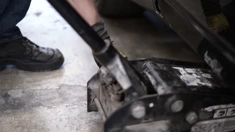 slowmotion bokeh shot of a mechanic placing a car jack and jacking