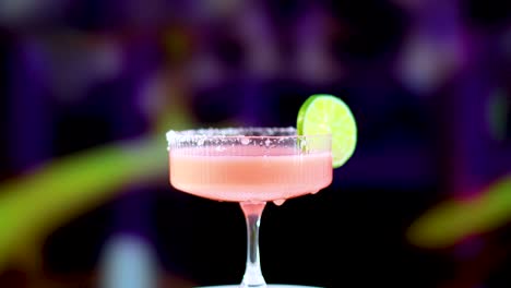 a pink margarita cocktail with a lime slice, set against a colorful, blurred background