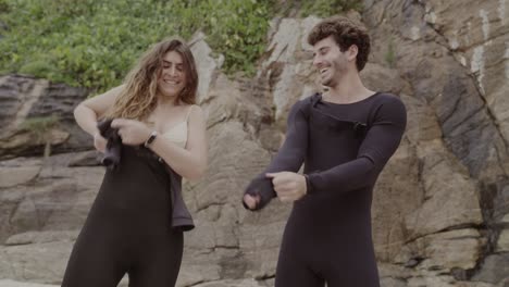 couple getting ready for surfing on a rocky beach
