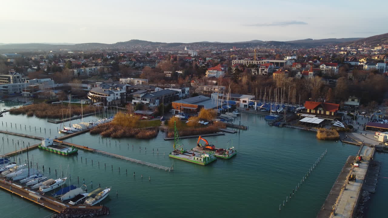 Wide drone view of Balatonfured waterfront with colorful buildings and sunset-lit water