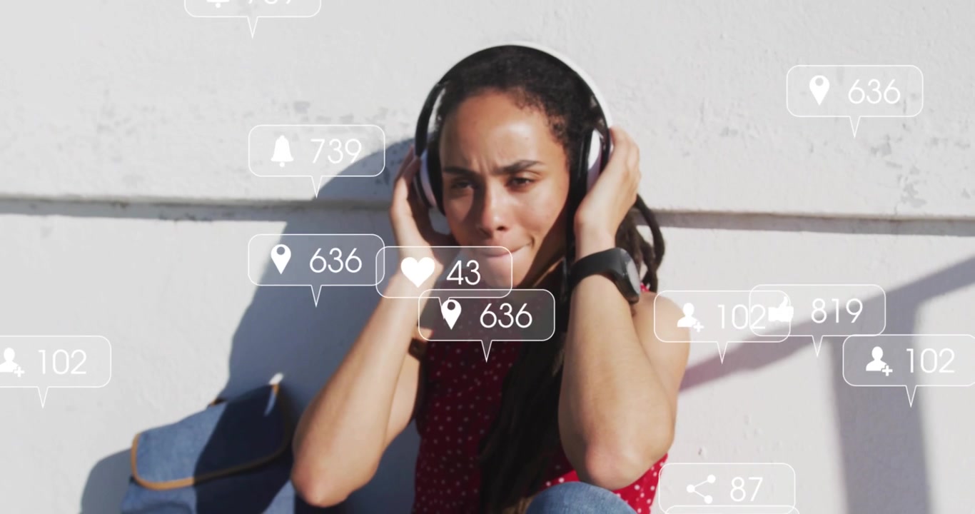 Siddende kvinde justerer hovedtelefoner, aktiverer ikoner, der overvåger engagement på sociale medier omkring hende.
