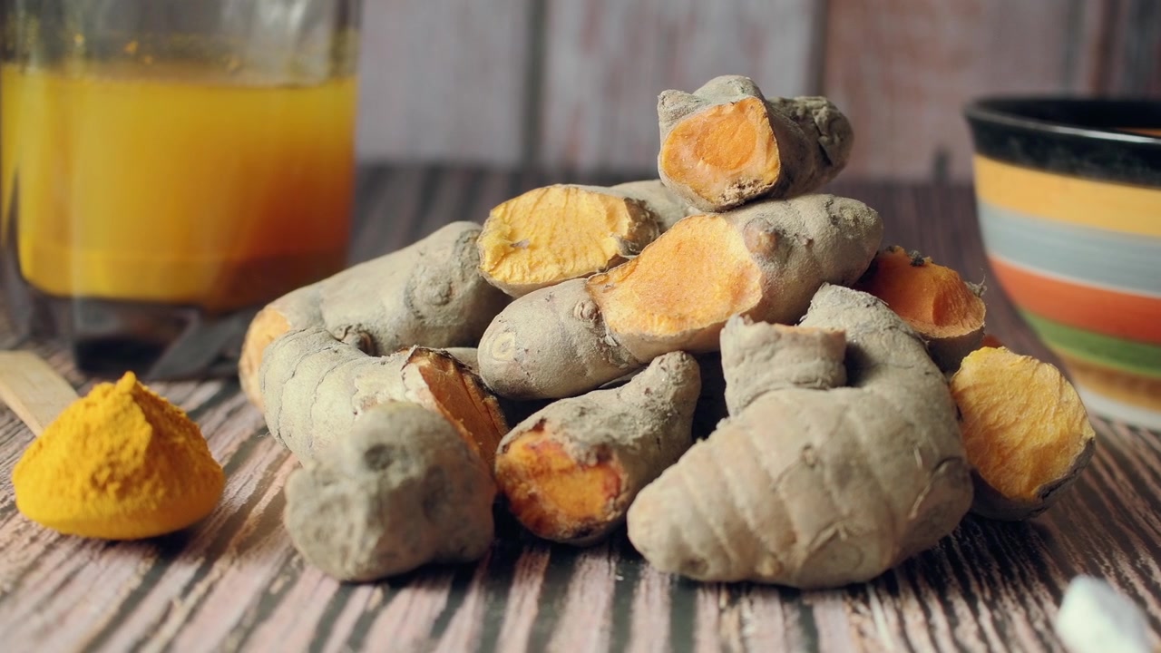 Fresh Turmeric Roots and Powder on Wooden Table