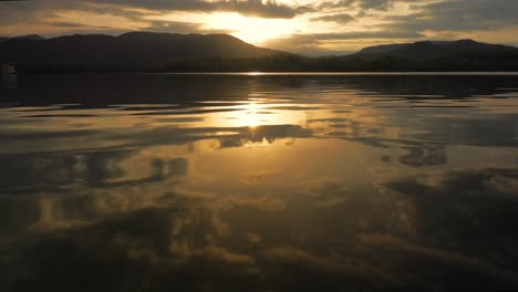 hermosa puesta de sol reflejada en el lago con montañas