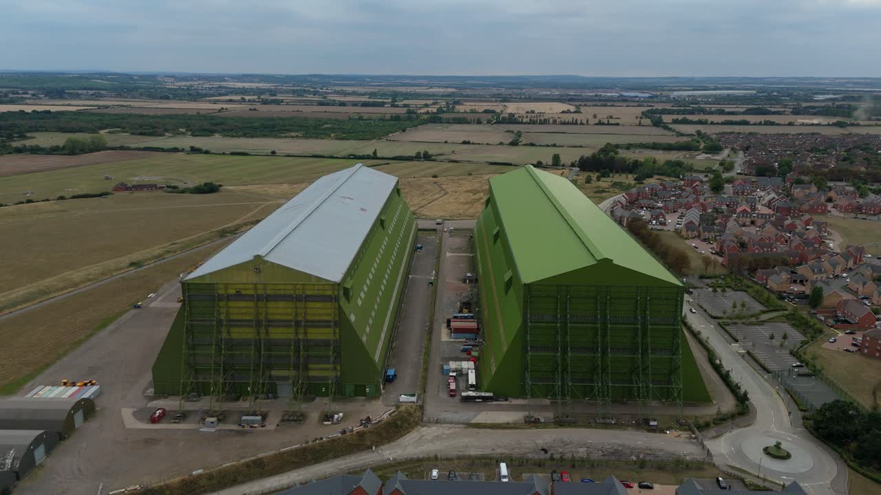 Drone footage of large film studios, hangars, and movie sets surrounded by countryside and houses near Bedford England UK in summer light
