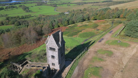 Lonely-stone-tower-building-on-hillside-with-slow-flight-towards-and-pan-up-revealing-countryside-beyond