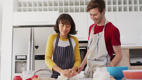 Video-of-happy-diverse-couple-baking-together-in-kitchen