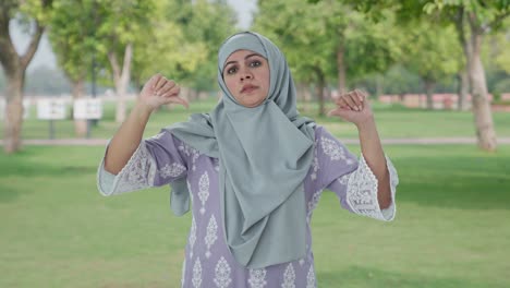 disappointed muslim woman showing thumbs down in park