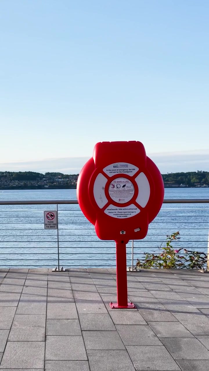 Rød redningskransstation på en havnefrontspromenade med udsigt over havet