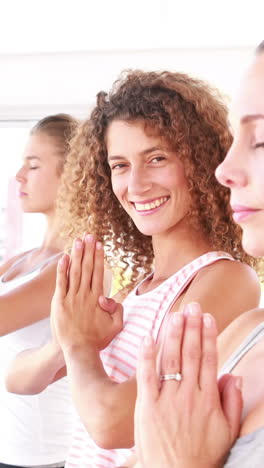 mujeres atléticas sonrientes de pie en posición de yoga