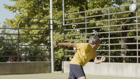 senior football player hitting ball with head while the goalkeeper catching it