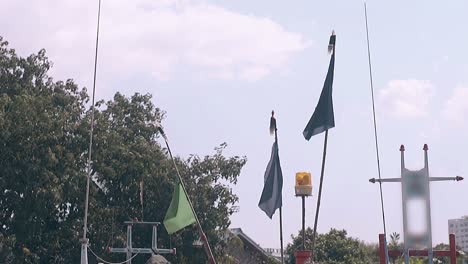 blue and yellow flags waved by wind against green trees