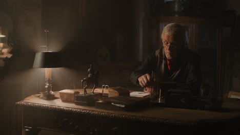 older passionate man evaluates an old watch in his office at night
