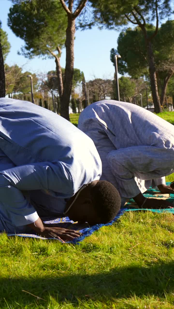 Muslim men praying outdoors in a park