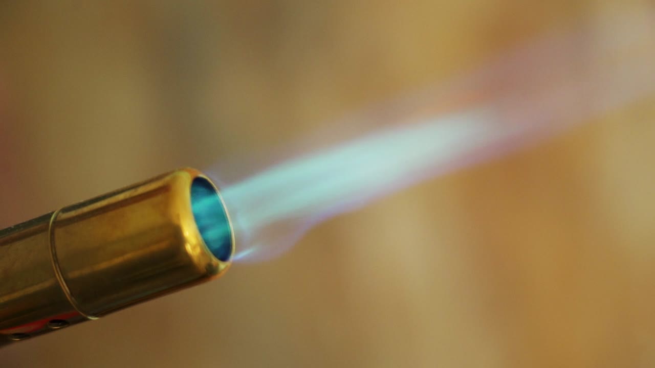 Close-up of a gas torch with a blue flame