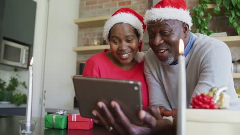 Feliz-Pareja-De-Ancianos-Afroamericanos-Con-Sombreros-De-Santa-En-Videollamada-En-Tableta-En-Navidad