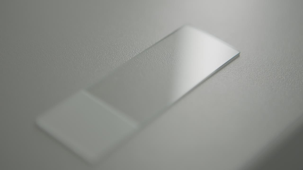 Glass microscope slide on a smooth surface under soft lighting in a close-up shot