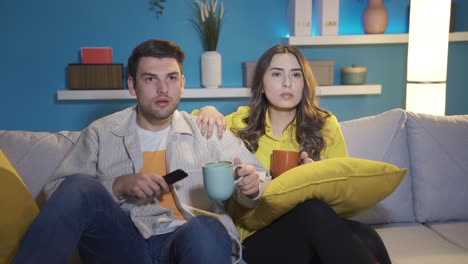 the couple watching television rejoice at the good news or event they see on the screen. getting good news on tv.