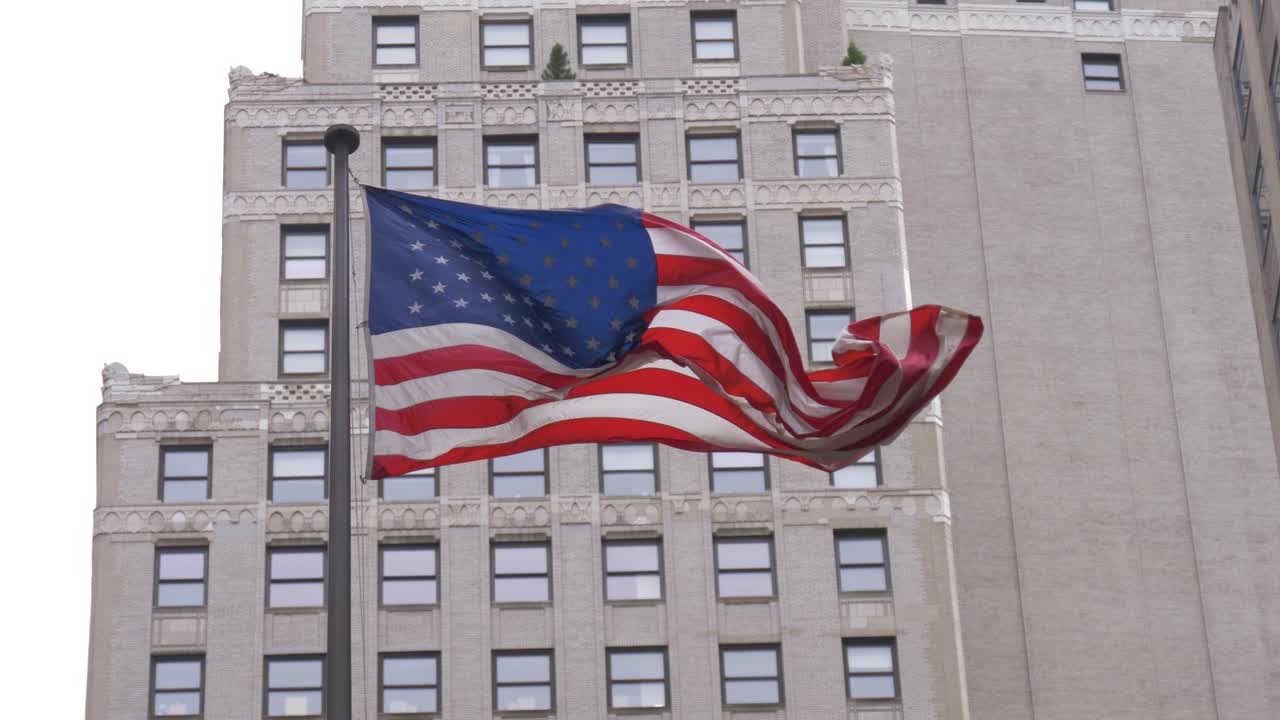 Flag of the United States waving in the wind in slow motion with an office building in the background in downtown Manhattan, New York City, USA