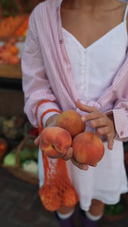 woman holding peaches at a farmer's market