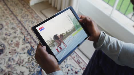 Compuesto-De-Un-Hombre-Sentado-En-Casa,-Viendo-Un-Evento-De-Atletismo-En-Una-Tableta