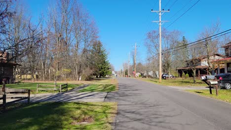 POV-shot-while-walking-on-road-surrounded-by-rows-of-cottages-on-both-sides-with-beautiful-green-lawn-at-daytime