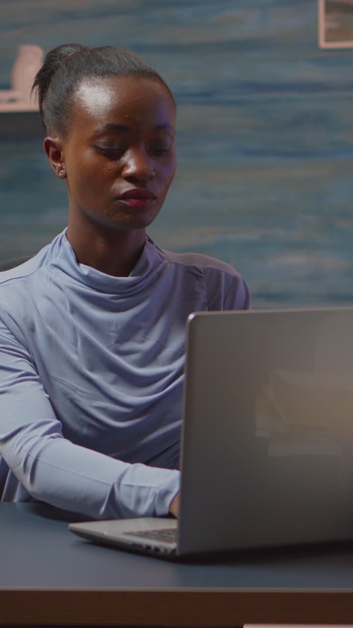 Vertical video: African-american woman looking at camera smiling working at pc