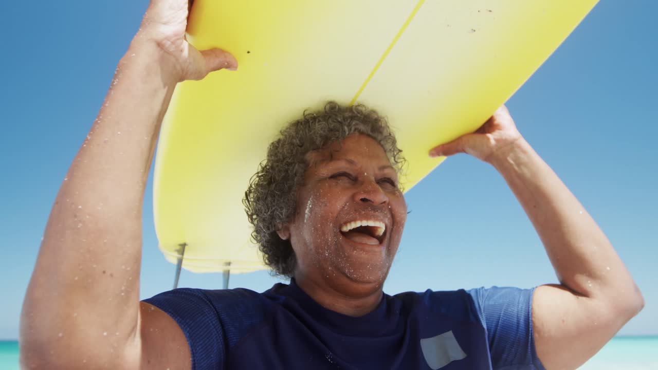 mujer mayor con una tabla de surf en la playa