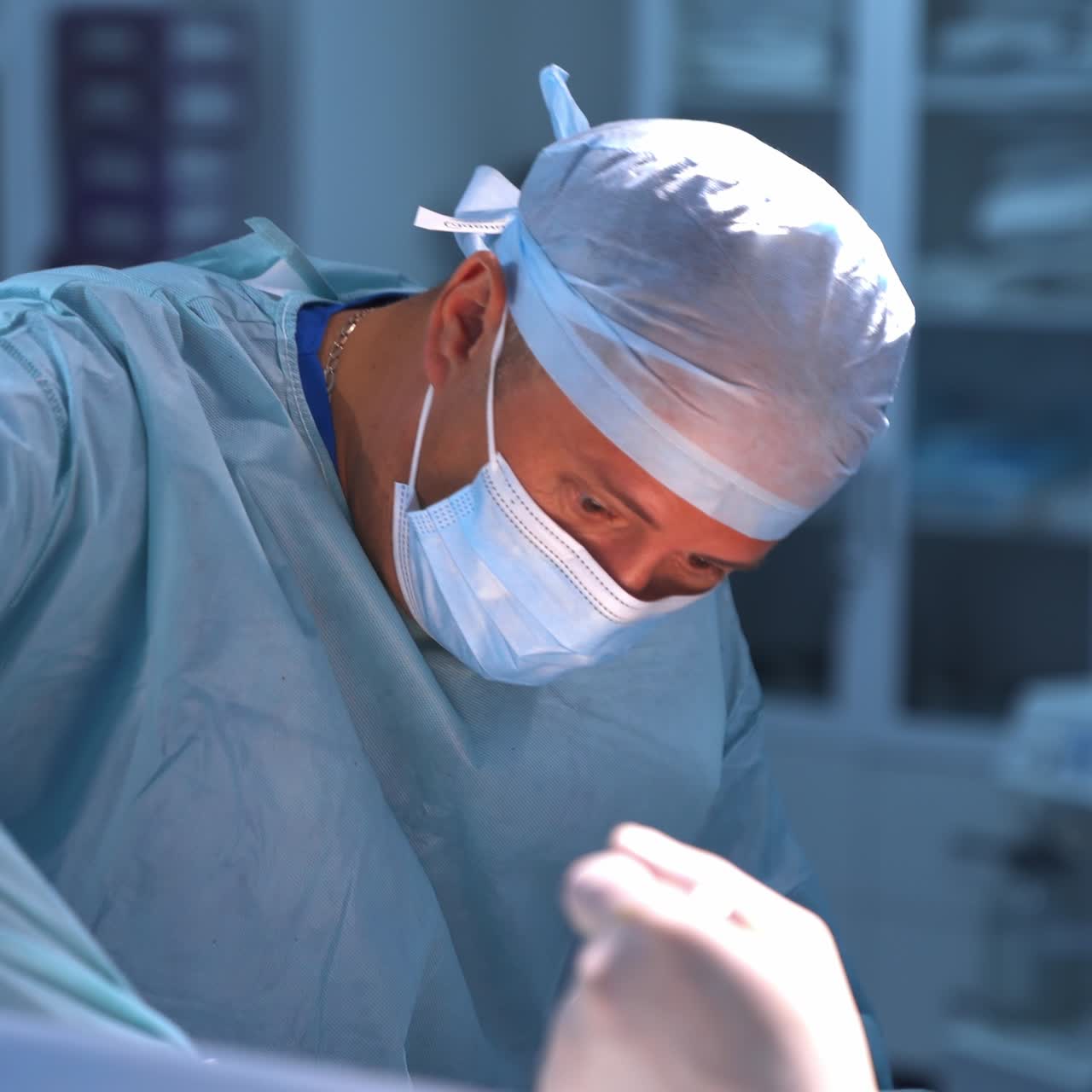Professional plastic surgeon working hard during operation. Hospital operating theatre in blur at the backdrop