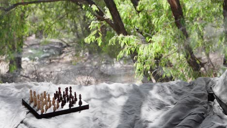 Chess-board-sitting-on-the-edge-of-bed-with-forest-backdrop-in-the-window