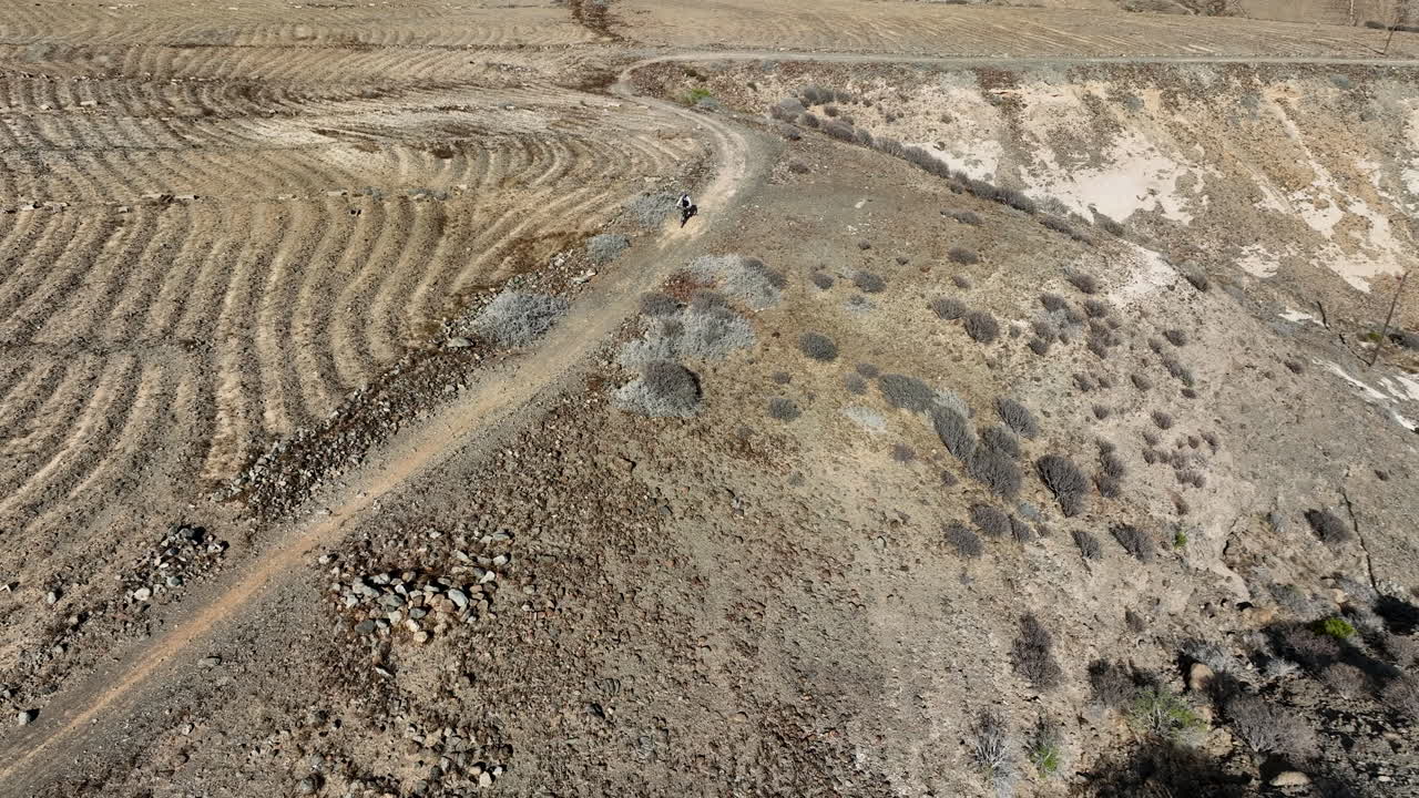 fantástica foto aérea de media distancia de un hombre con su bicicleta de montaña que viaja por una carretera en un paisaje desértico
